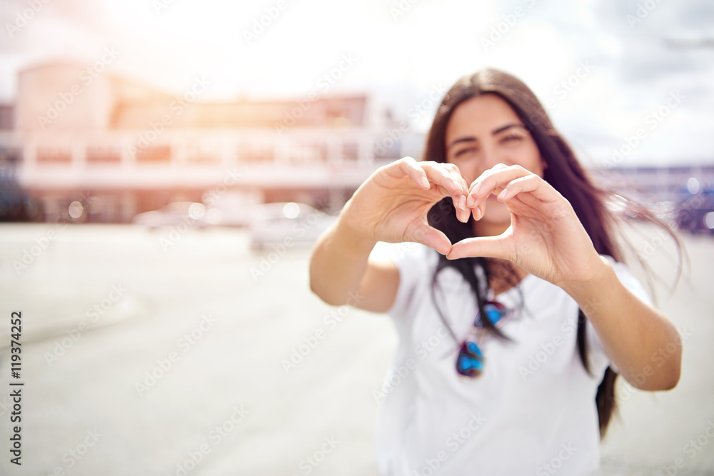 Pretty romantic young woman making a heart sign