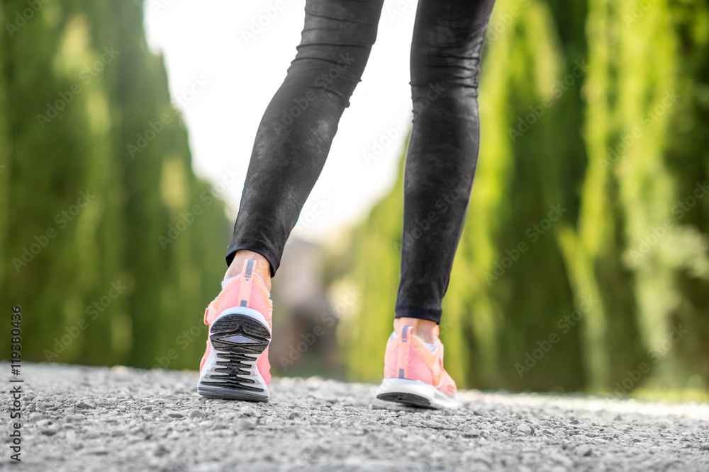 Female legs in sport sneakers in start position on the gravel road