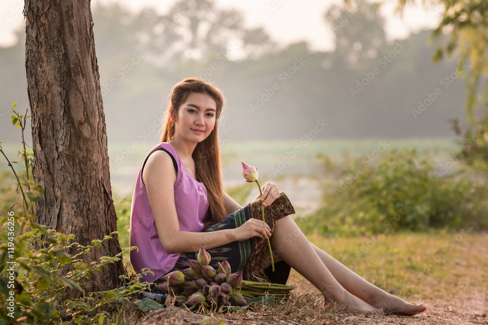 美丽的女孩坐在地板上看着莲花。