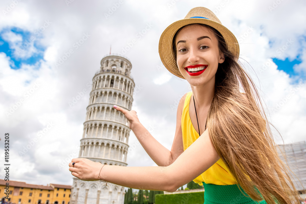 Young female traveler having fun in front of the famous leaning tower in Pisa old town in Italy. Hap