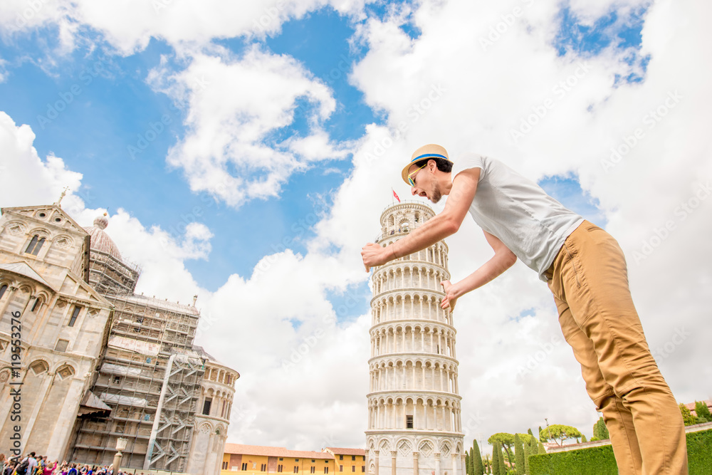 Man having fun with the famous leaning tower in Pisa old town in Italy. Happy vacations in Italy