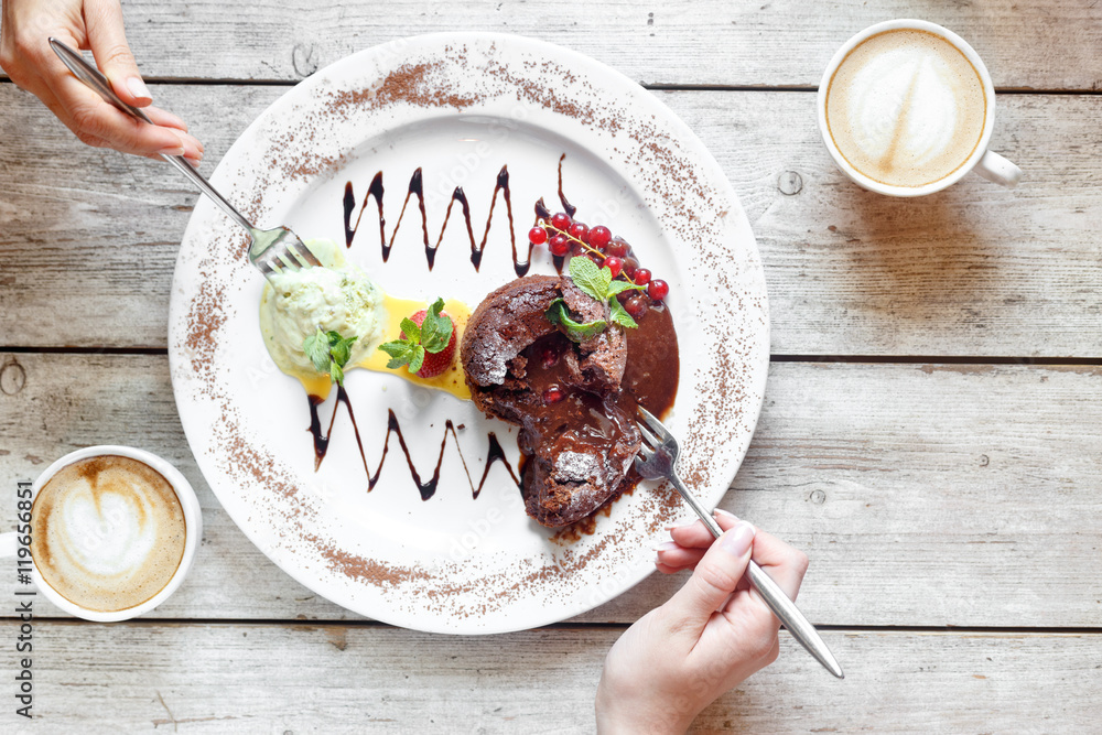 Sweet dessert and coffee on the wooden table with hands