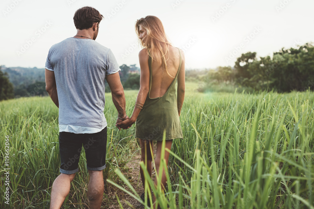 Young couple walking through grassy road