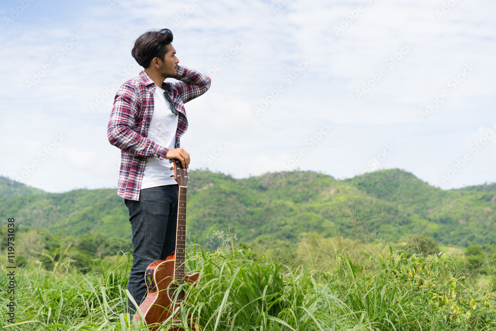 Young man holding guitar in mountain view