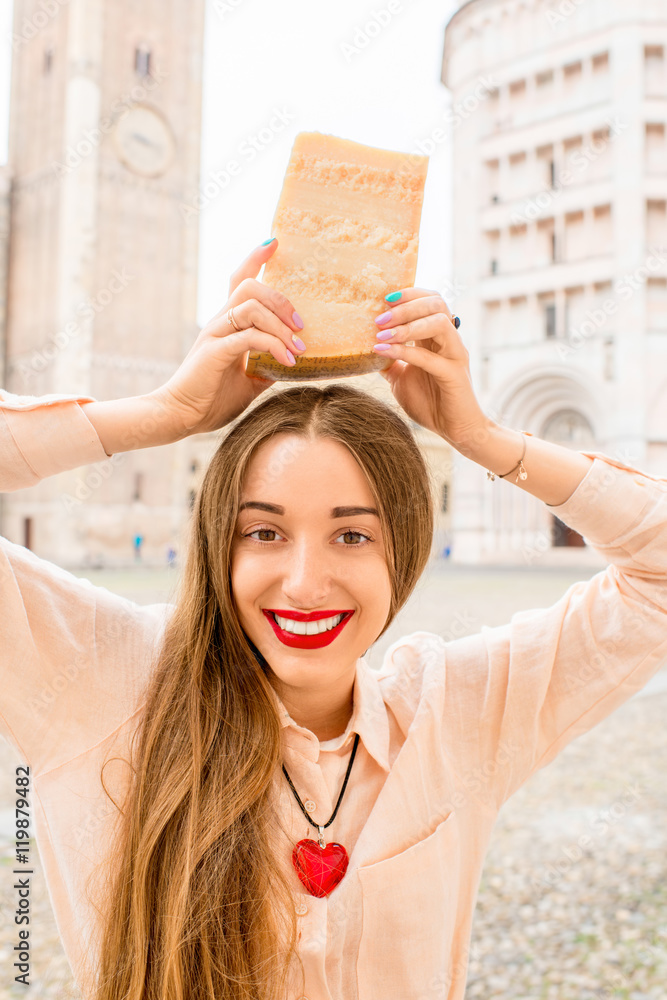 Young woman holding a piece of Parmesan cheese at the main square in Parma town in Italy. Parmesan i