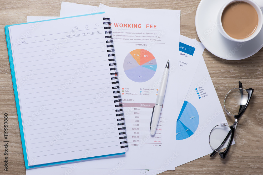 Business graphs and charts on a wooden desk with notebook, coffe