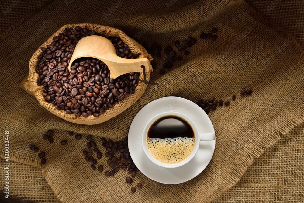 Top view of cup of coffee and coffee beans on burlap background