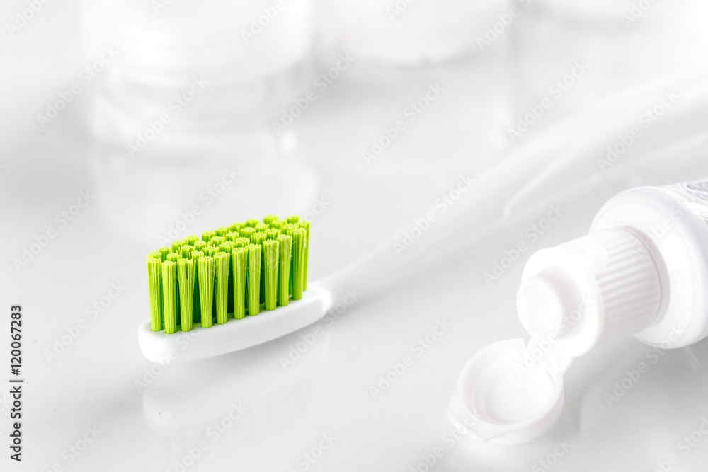 toothpaste and green toothbrush on white background