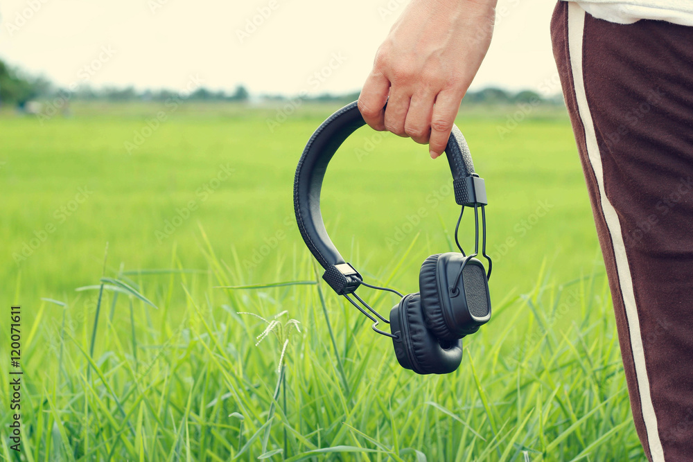 woman hand holding wireless headphone on green nature background