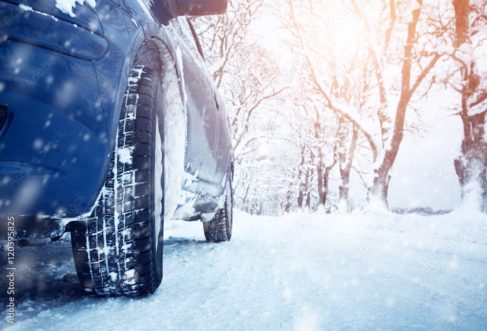 冬季道路上的汽车轮胎被雪覆盖。早上下雪时，车辆在雪地小巷上行驶