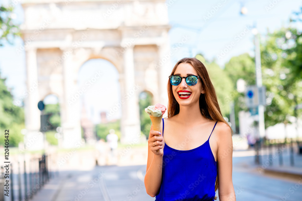 米兰凯旋门前，身穿蓝色连衣裙的年轻女子在吃冰淇淋。街头美食