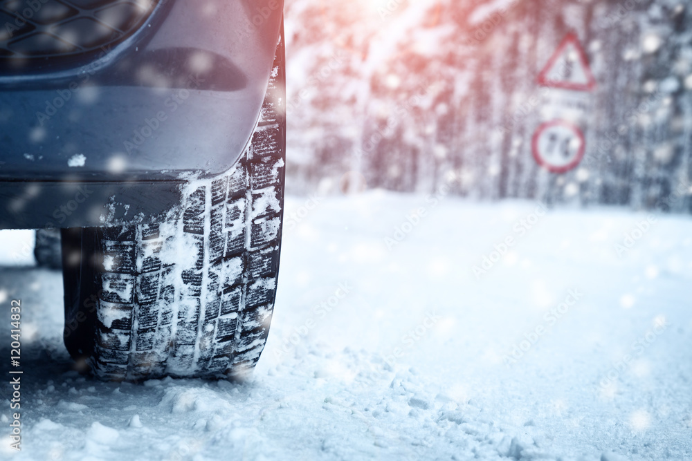 Car tires on winter road covered with snow. Vehicle on snowy alley in the morning at snowfall