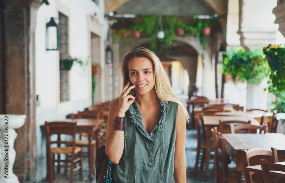 Donna bionda passeggia e parla al telefono 