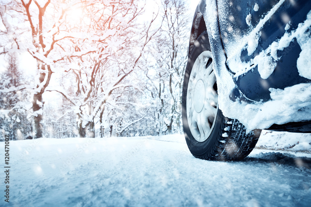 冬季道路上的汽车轮胎被雪覆盖。早上下雪时，车辆在雪地小巷上行驶