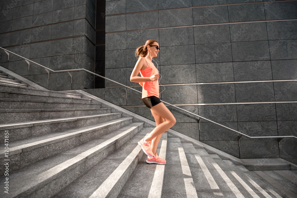 Young sports woman running down the stairs in the modern city. Healthy lifestyle and morning jogging