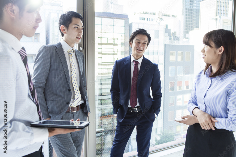 Four businessmen who are the stand talking in the office