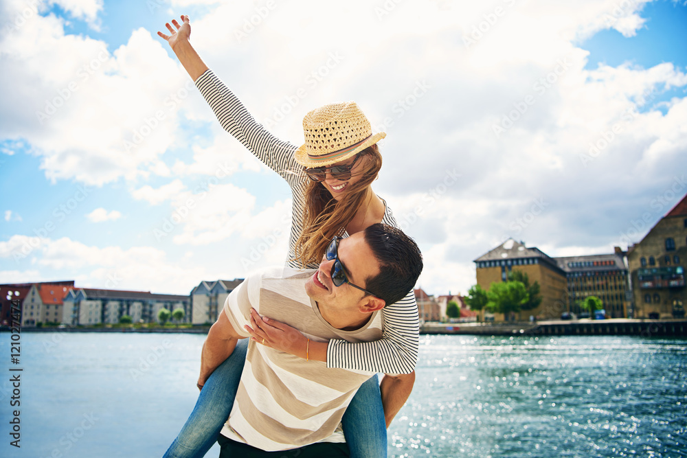 Fun loving young couple frolicking at a waterfront