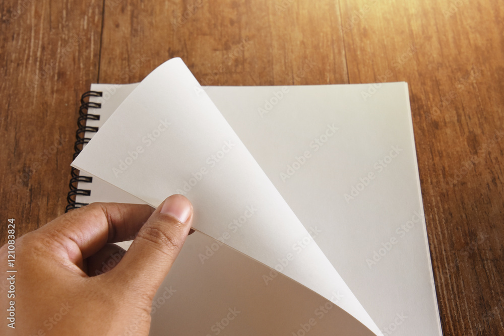 Hand open notebook on wood table