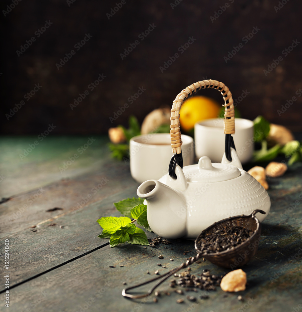 Teapot and cups of tea with mint and lemon