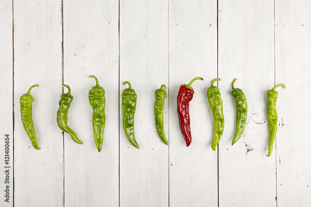 Leadership concept - red hot chili pepper leading the group of green ones