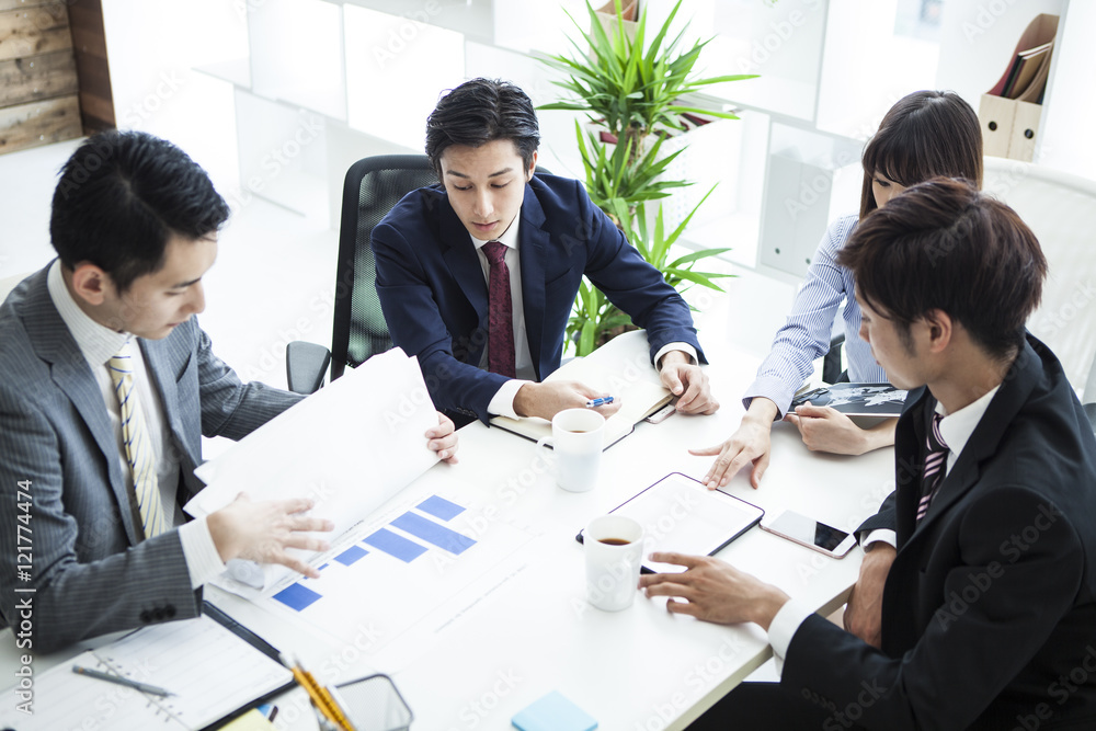 四位年轻商人边看平板电脑边开会