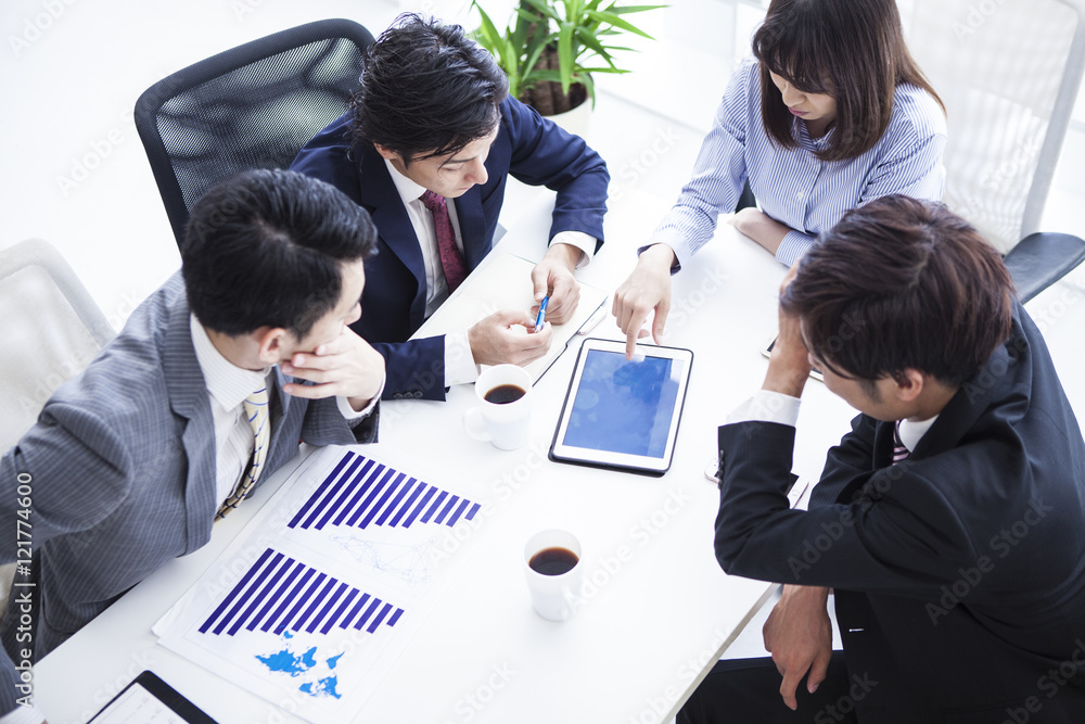 四位年轻商人边看平板电脑边开会