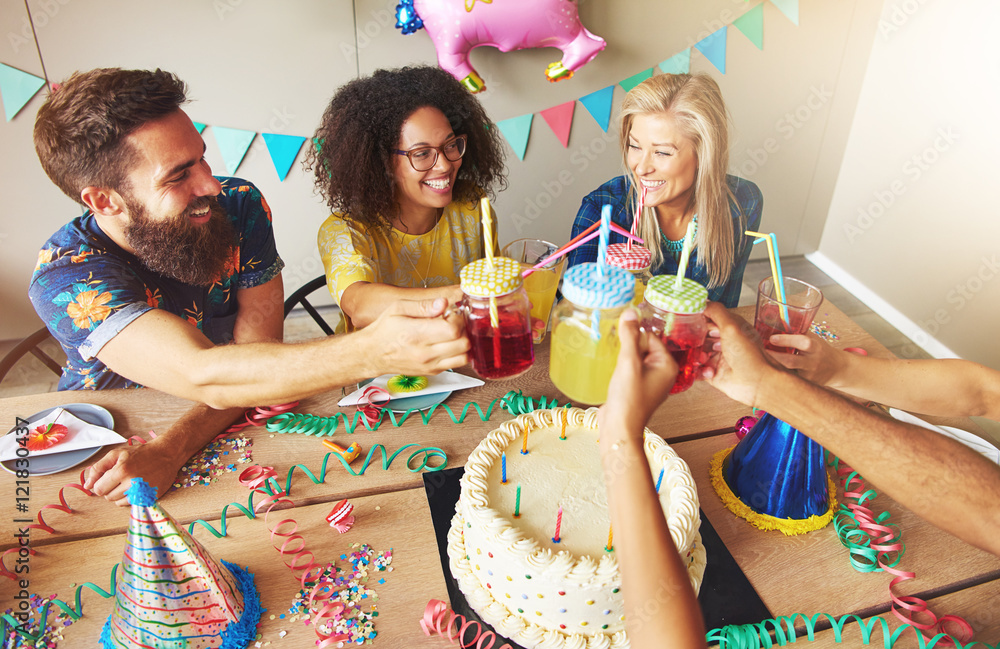 Happy friends holding drinks over cake