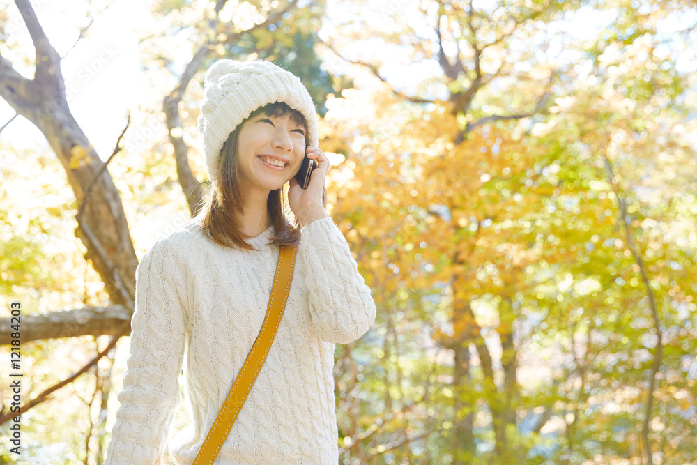 スマートフォンで話す女性　紅葉背景