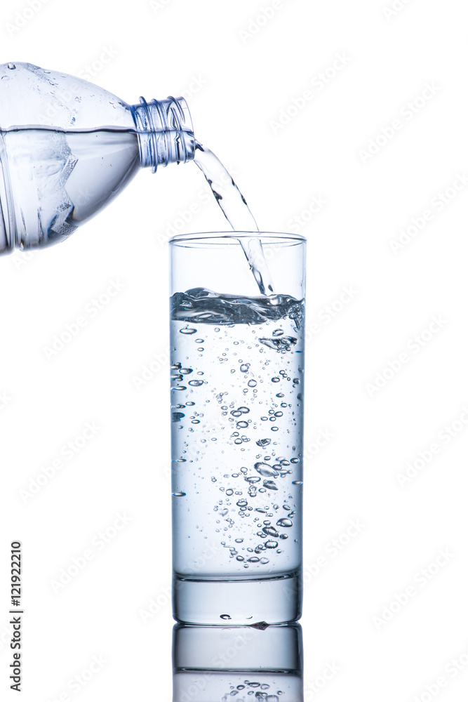 Drinking water is poured into a glass from bottle