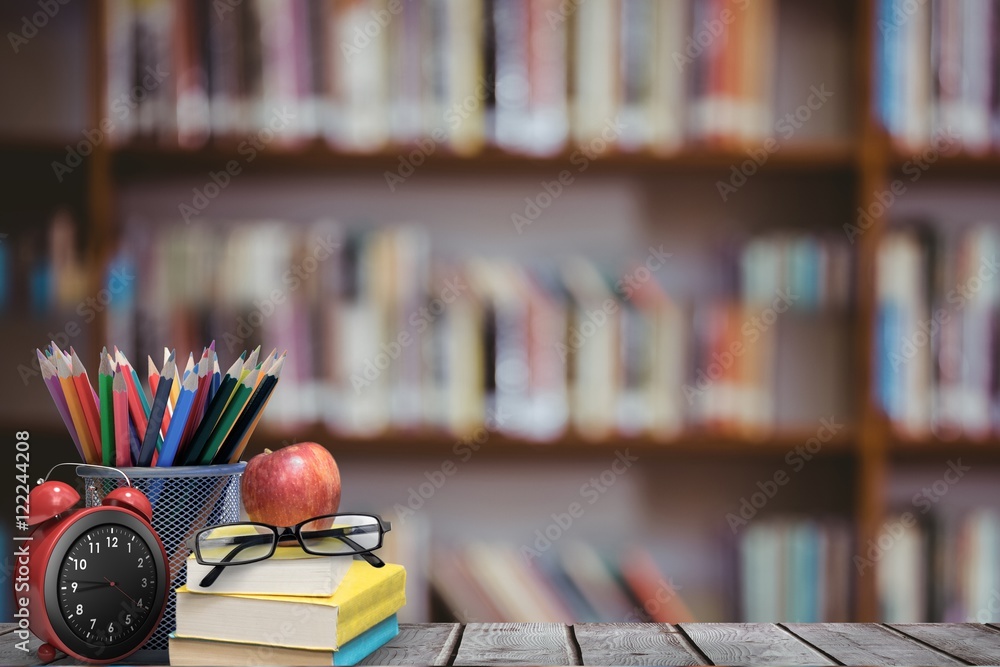 School materials and apple with library background