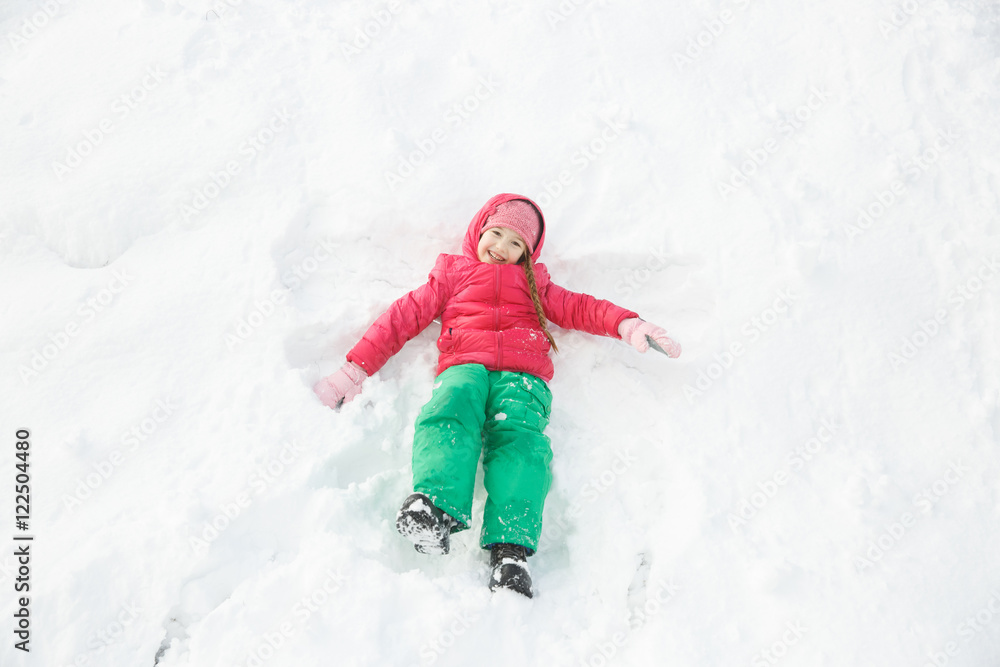 Playful girl playing in snow, making a snow angel