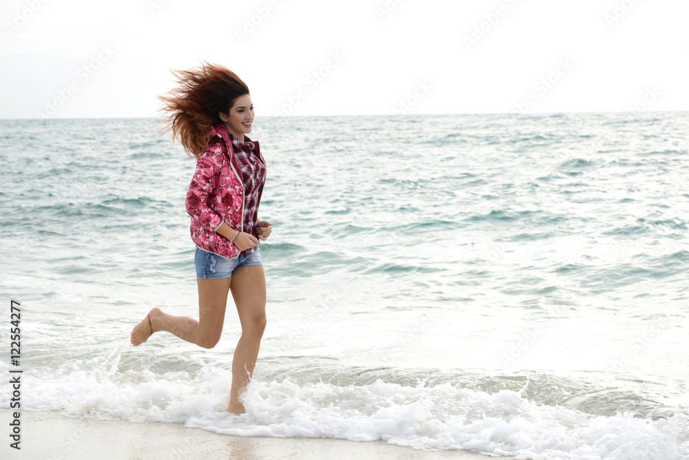 beautiful girl with colorful windbreaker running on the beach