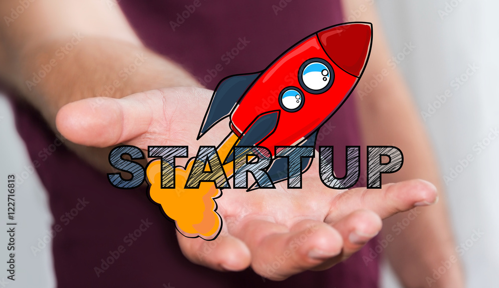 Businessman holding hand drawn startup text and red rocket