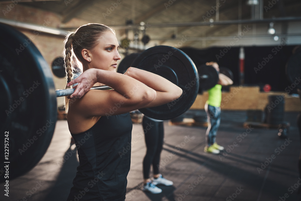 Woman pulling up large barbell in fitness class