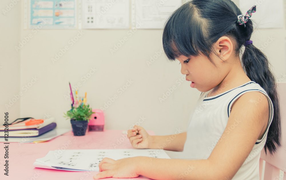 Young school girl reading a book at home with vintage color effect