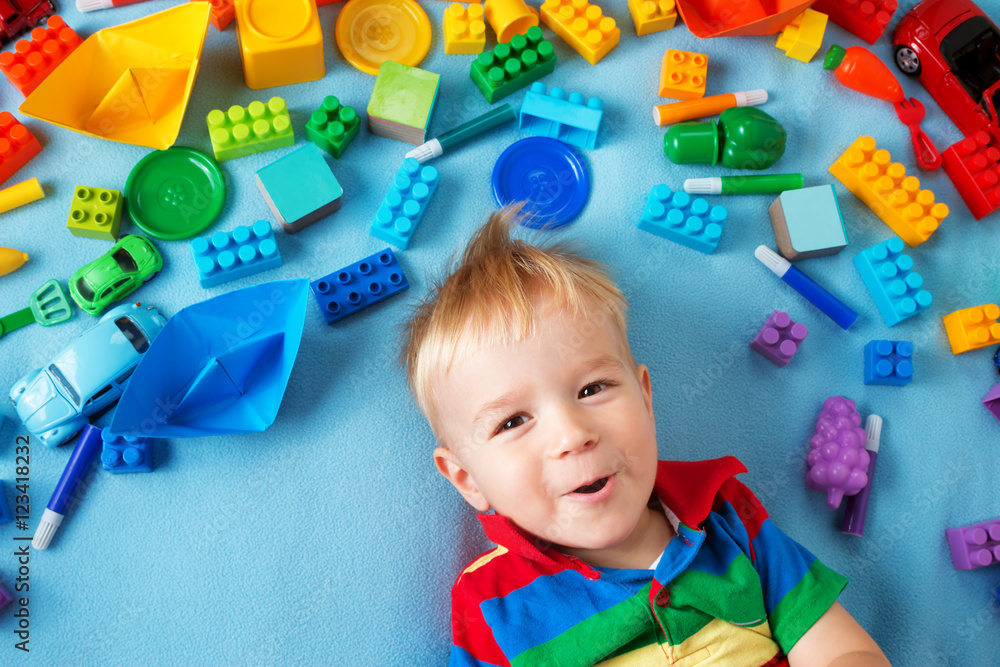 Baby boy lying on the blanket with many toys around