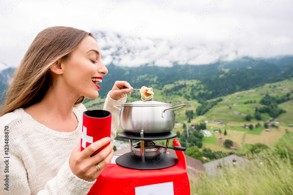 一名年轻女子在瑞士山区旅行时吃火锅，这是一顿传统的瑞士大餐