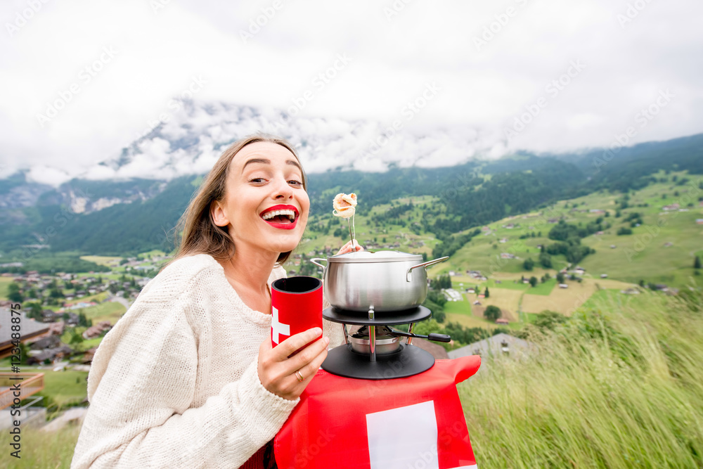 一名年轻女子在瑞士山区旅行时吃火锅，这是一顿传统的瑞士大餐