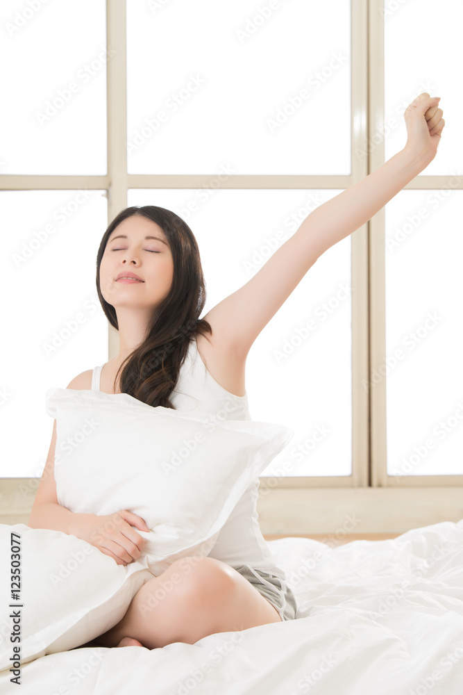 beautiful asian woman stretching and holding pillow in morning