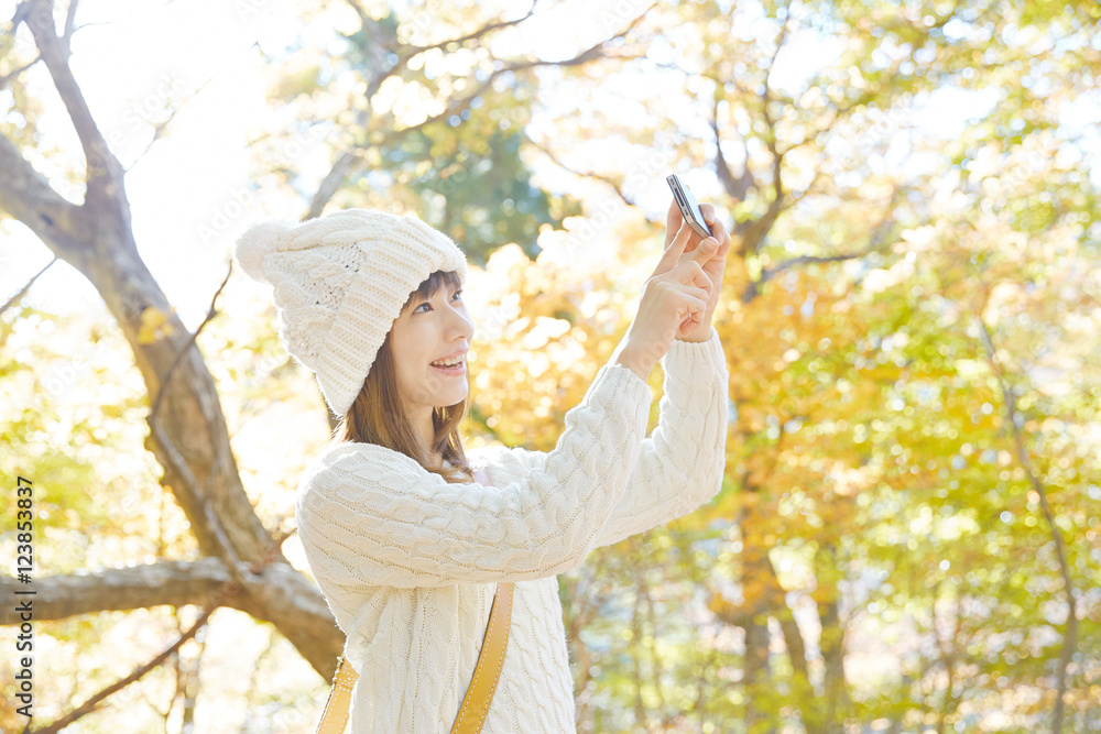 紅葉をスマートフォンで撮る女性