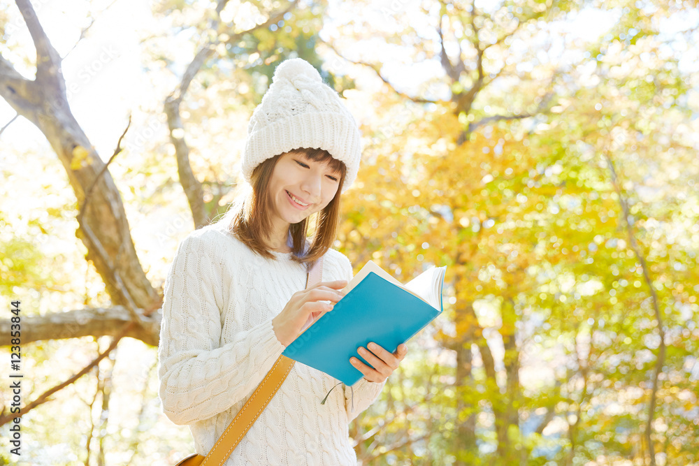 紅葉の中で読書する女性