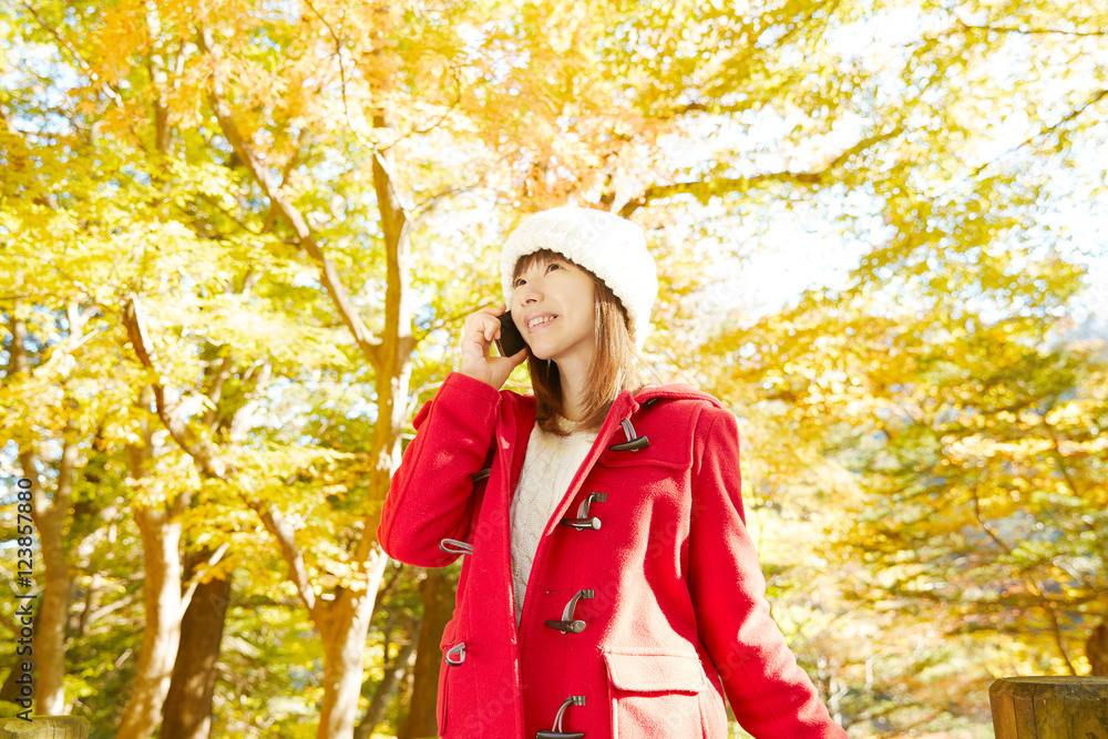 スマートフォンで話す女性　紅葉背景