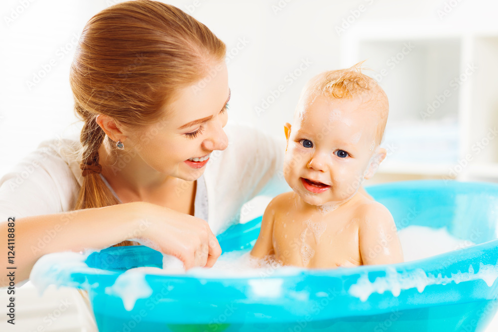 Happy family mother bathes the baby in  bath