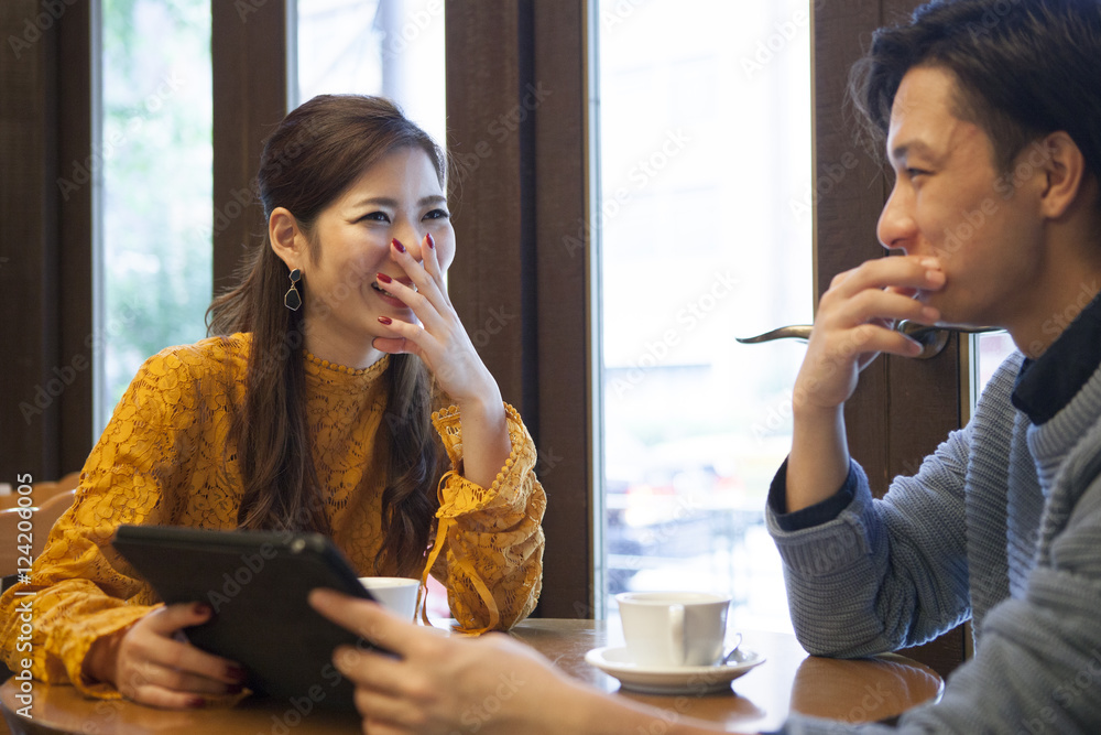 年轻夫妇在咖啡馆一起看电子平板电脑