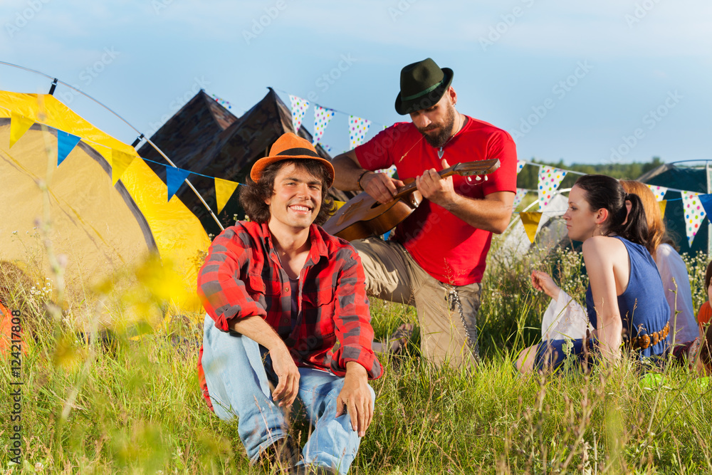 Young man sitting on grass at fest with friends