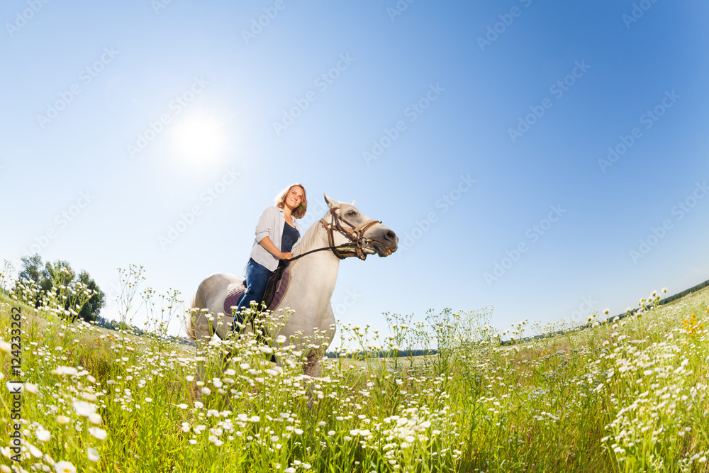 Pretty woman horseriding in the flowery meadow