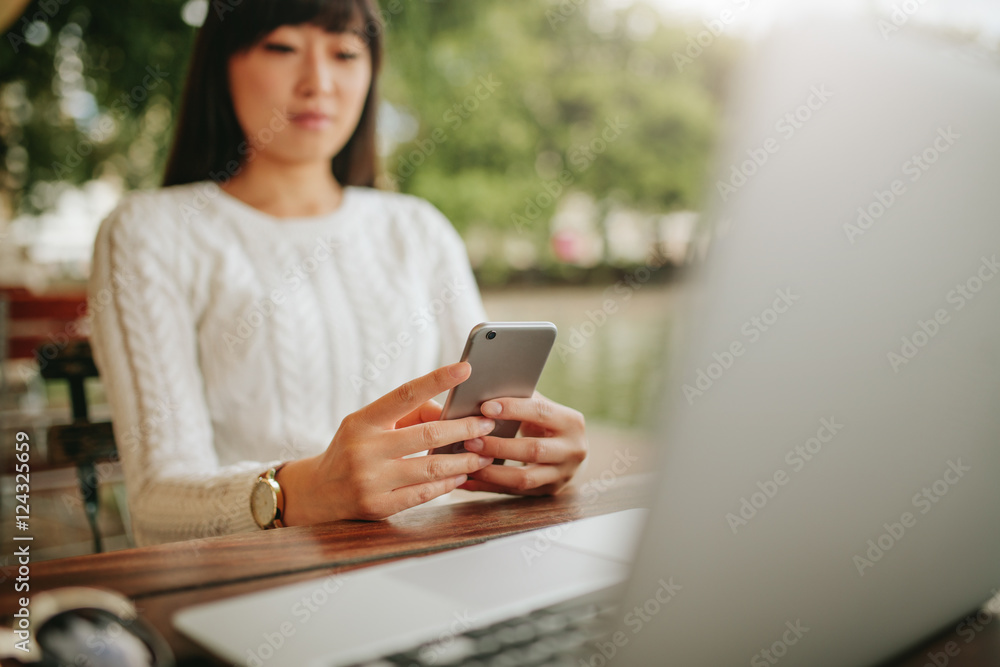 Asian woman using mobile phone at outdoor cafe