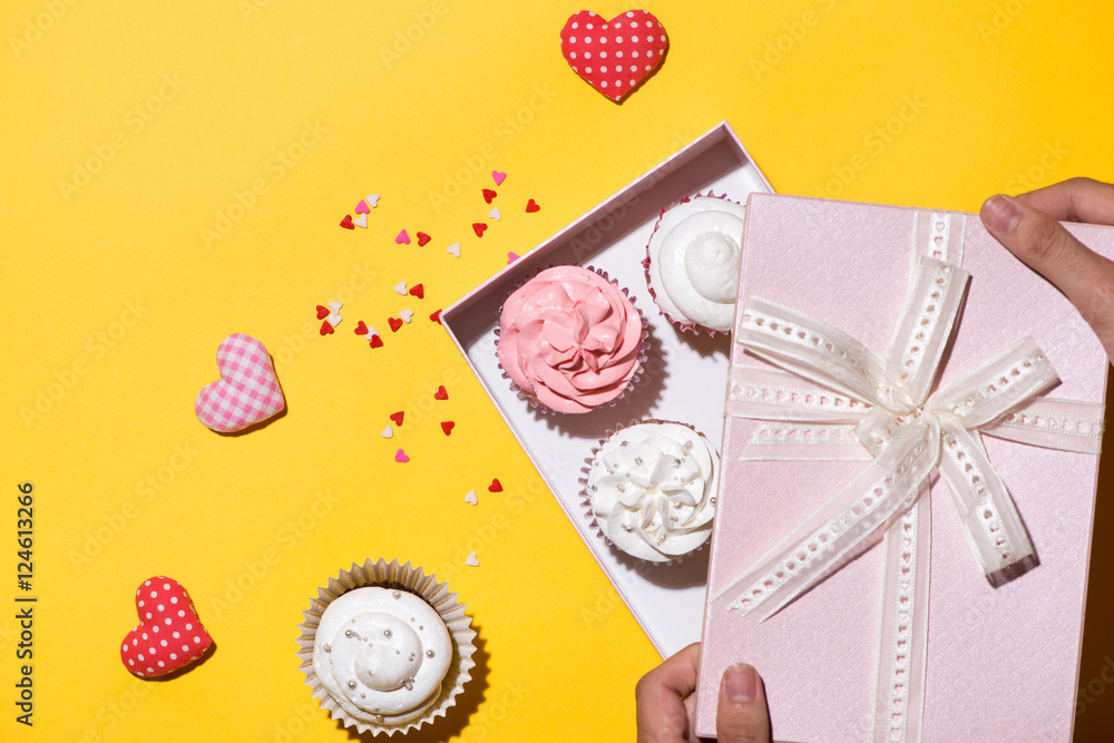 Delicious cupcake with paper box on yellow background