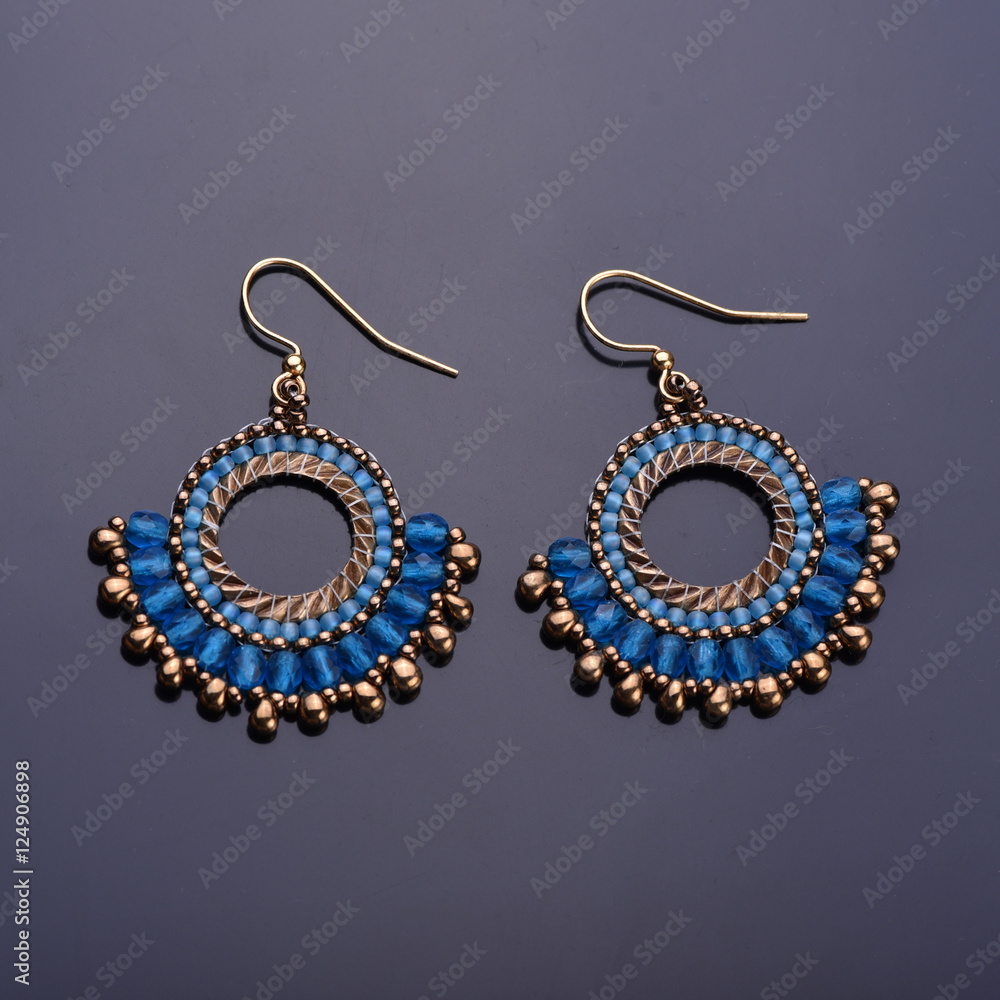 Beaded earrings blue on a dark background. Beadwork. Top view.