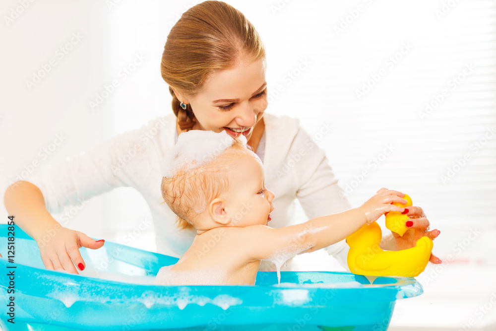 Happy family mother bathes the baby in  bath